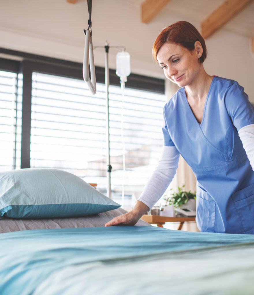 Portrait-of-female-nurse-or-housekeeping-staff-changing-sheets-in-hospital.